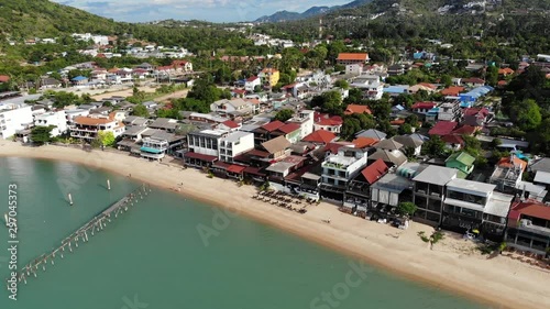 Fisherman village on seashore. Aerial view of typical touristic place on Ko Samui island with souvenir shops and walking street on sunny day. Architecture in asia, local settlement drone view. photo