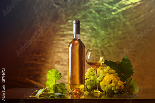 Wine. Bottle and a glass of white wine with ripe grapes still life. White wine on a dark background. The boundaries of art design