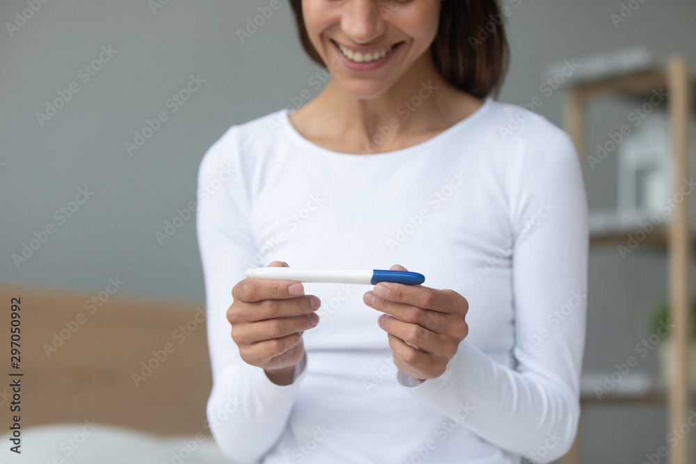 Smiling millennial biracial woman holding plastic test in hands. Smiling millennial biracial woman holding plastic test in hands.