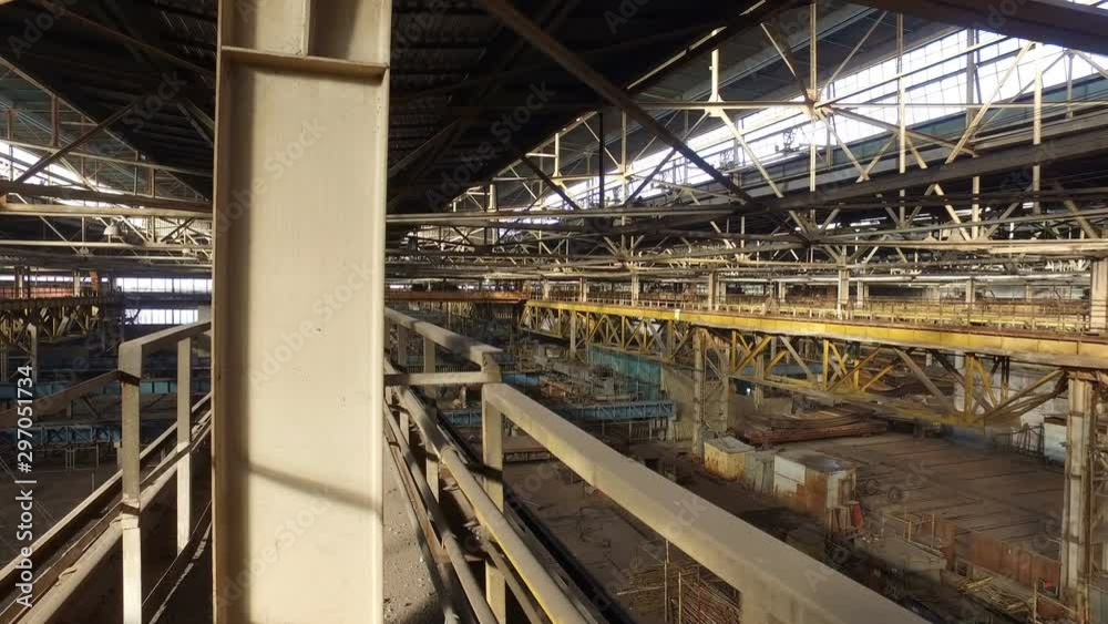 View and movement from top platform at factory. Metal structures, beams, poles and mechanisms in huge hangar of an old abandoned shipyard View and movement from top platform at factory. Metal structures, beams, poles and mechanisms in huge hangar of an old abandoned shipyard