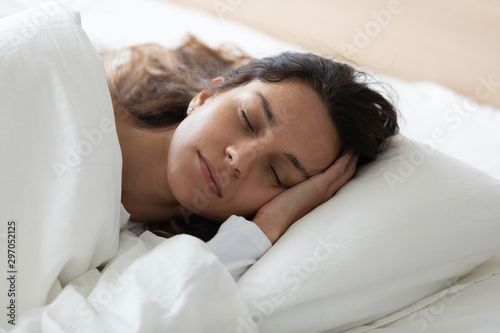 Side view tranquil young biracial woman lying in bed.