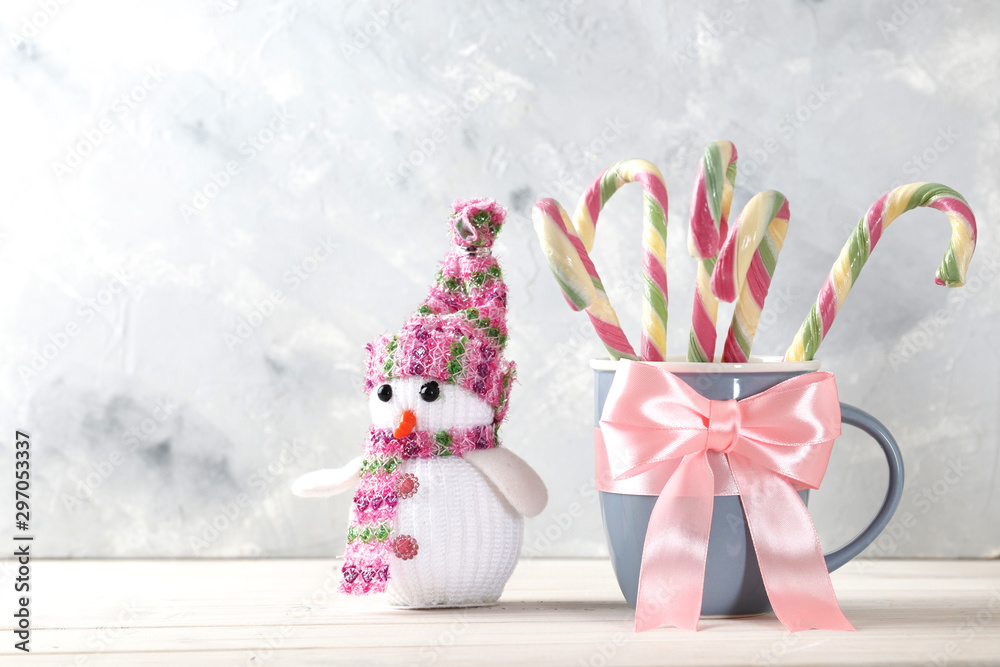 Composition with sweet candy cane, bow,  in a cup on color background