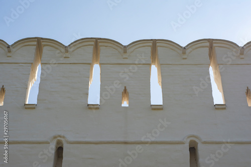 The upper part of the old defensive wall of white stone with Ghibelline merlons in the Italian style photo