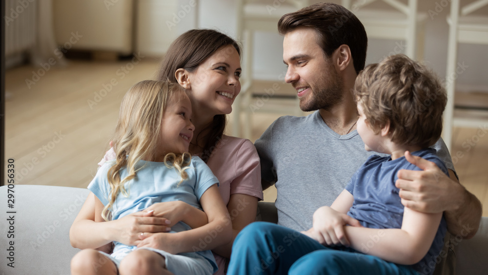 Happy parents with little daughter and son sitting on couch Happy parents with little daughter and son sitting on couch
