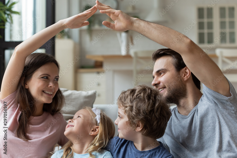 Smiling parents sitting with kids, making roof gesture with hands