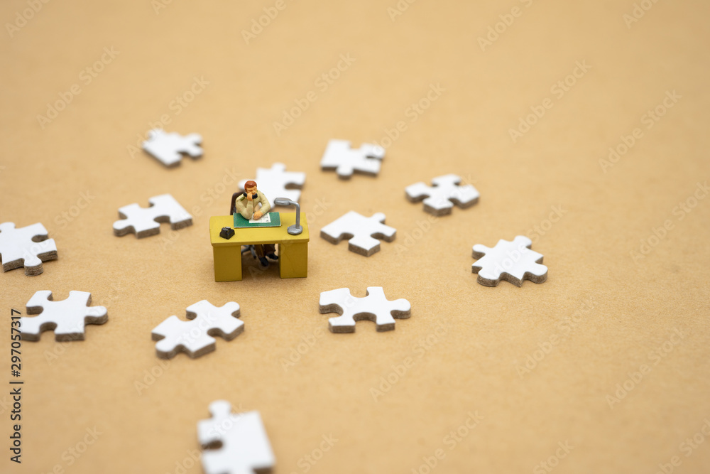 Miniature people businessmen standing on white Jigsaw. The concept used in selecting personnel to participate in the organization. with copy space. Miniature people businessmen standing on white Jigsaw. The concept used in selecting personnel to participate in the organization. with copy space.