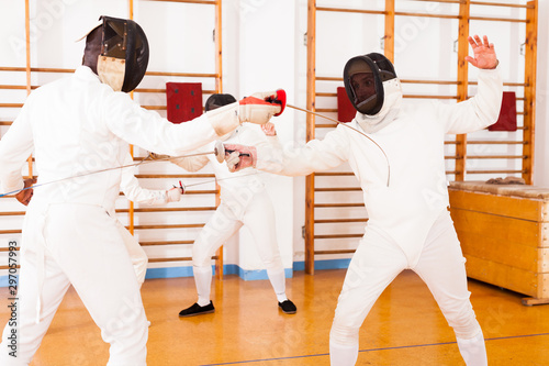 Athletes at fencing workout, practicing attack movements in duel