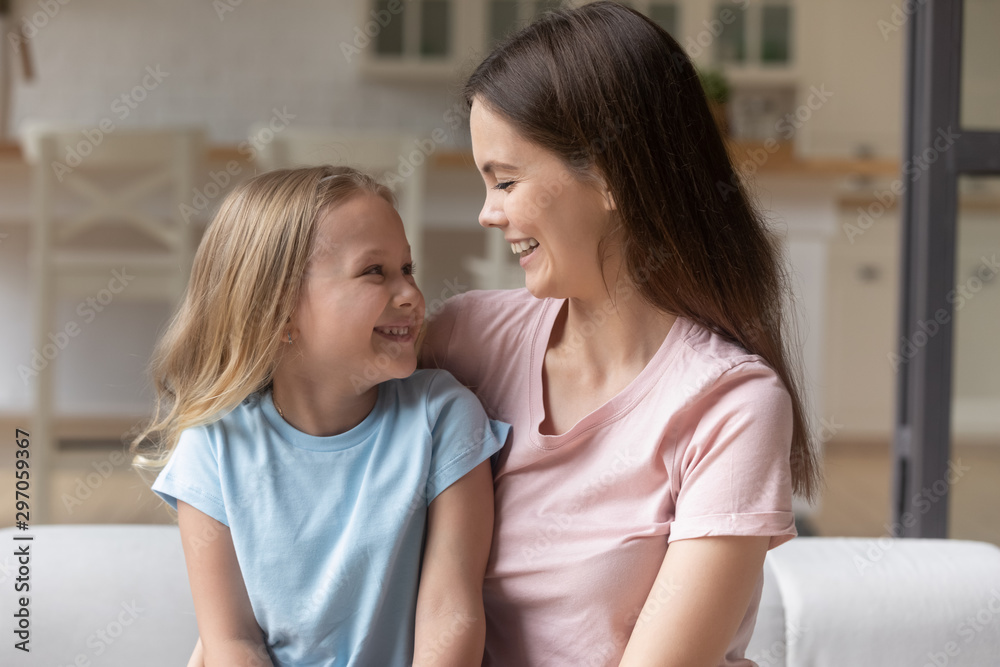 Smiling mother and little daughter hugging, looking at each other Smiling mother and little daughter hugging, looking at each other