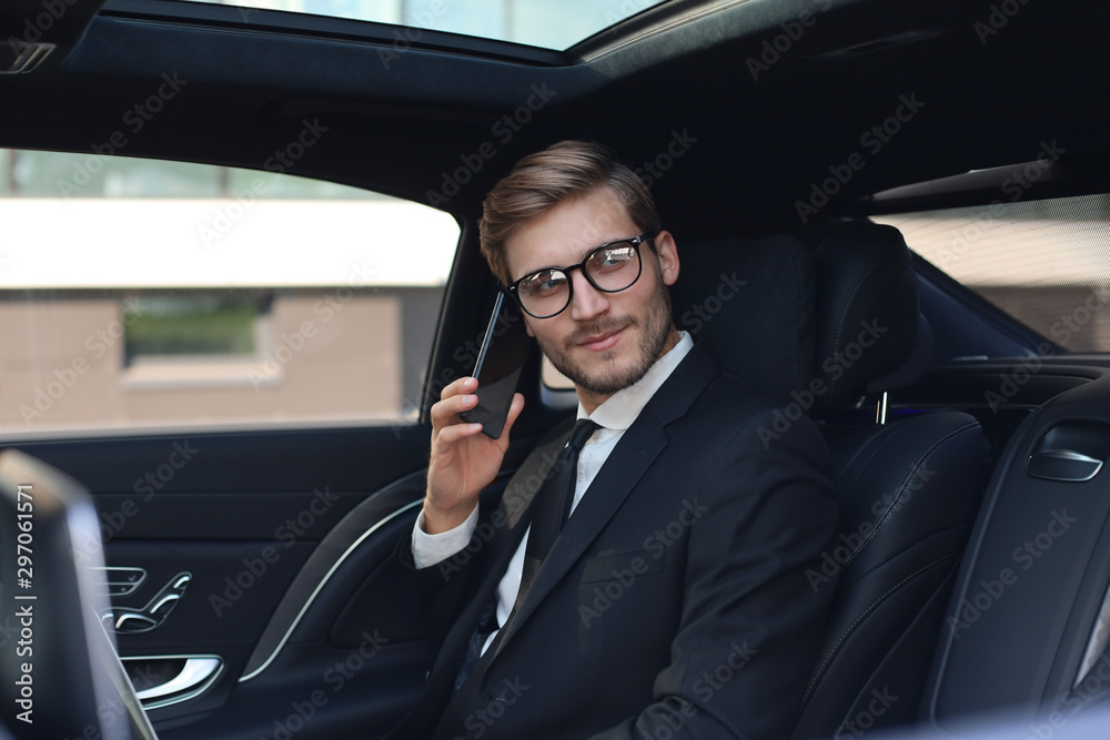 Thoughtful confident businessman talking on the phone while sitting in the car. Thoughtful confident businessman talking on the phone while sitting in the car.