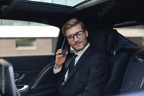Thoughtful confident businessman talking on the phone while sitting in the car. © ty