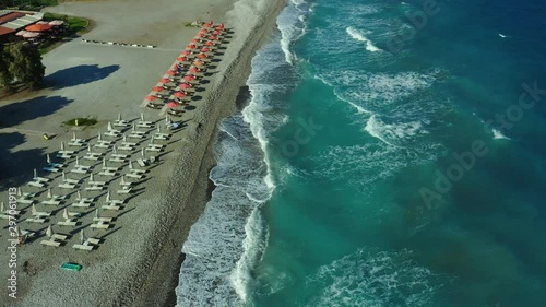 flying over a pebble beach with waves and surf, Rhodes island, Greece, views of coastline with hotels and umbrellas photo