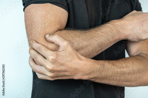Photography man with black t shirt and hand on elbow, injury concept