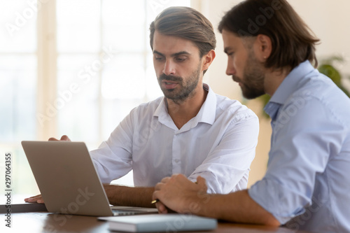 Focused businessman salesman consult male client show presentation on laptop