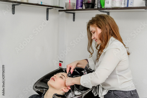 beauty and people concept-happy young woman with hairdresser washing head in hair salon. Beautiful young girl with a hairdresser washing the head at the hair salon