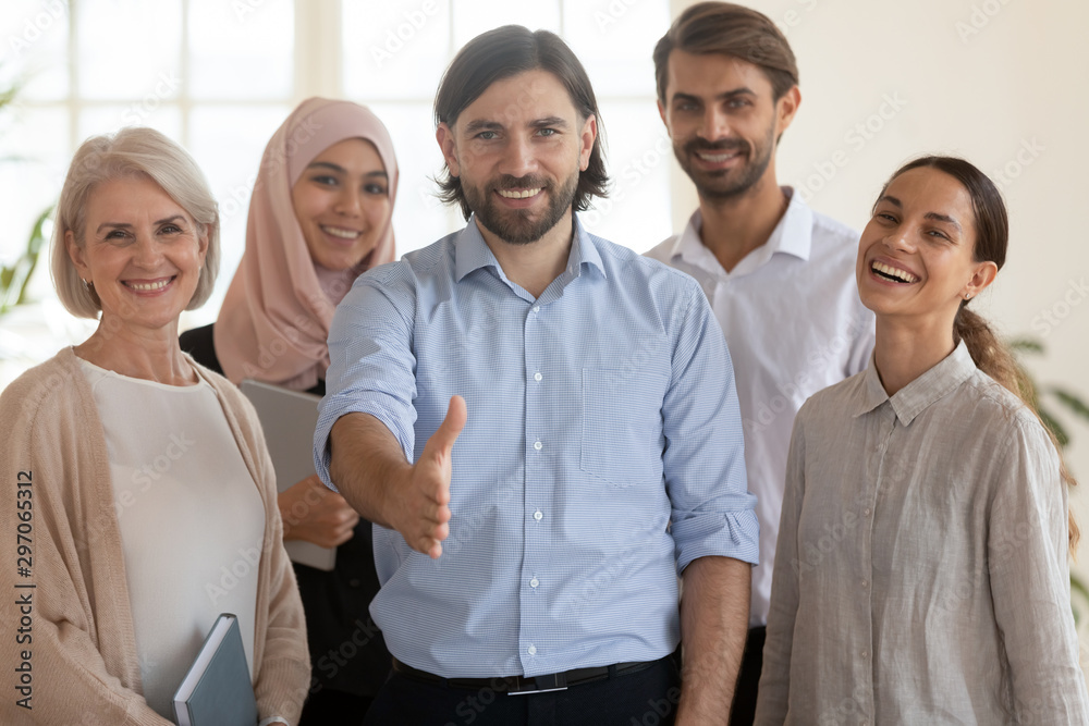 Happy ceo extend hand at camera stand with multicultural businesspeople Happy ceo extend hand at camera stand with multicultural businesspeople