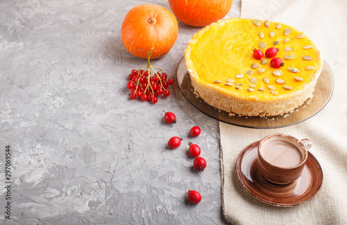 Traditional american sweet pumpkin pie decorated with hawthorn red berries and pumpkin seeds with cup of coffee on a gray concrete background. side view, copy space.