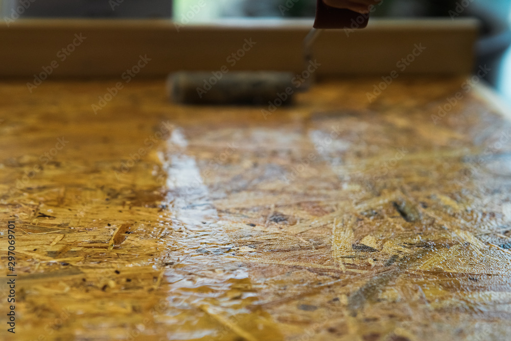 Roller paint brush lacquered osb wooden board. DIY, carpenting and construction concept. Roller paint brush lacquered osb wooden board. DIY, carpenting and construction concept.