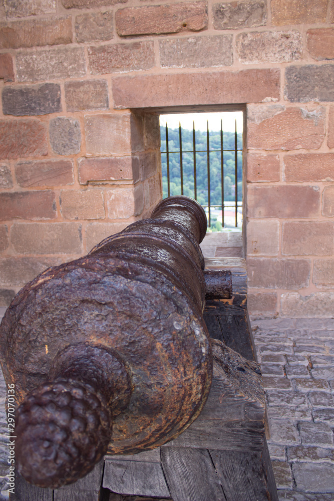 Old cannon pointing through an opening in a castle rampart in Germany
