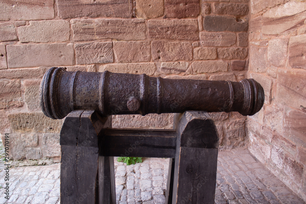 Old cannon pointing through an opening in a castle rampart in Germany