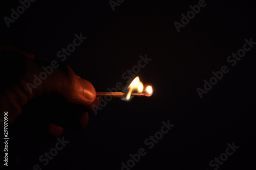 A lit match burns in the dark. On a black background.