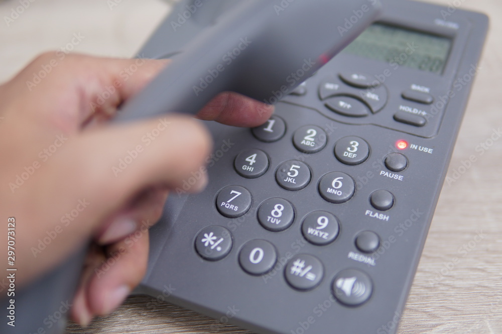 Male hand holding telephone and dailing a phone number. Male hand holding telephone and dailing a phone number.