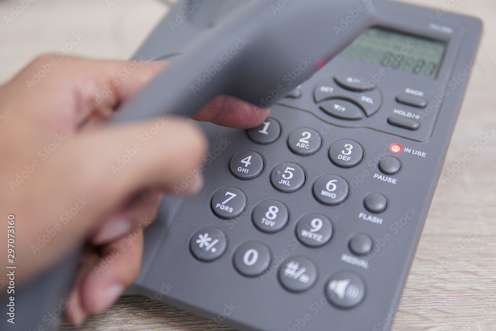 Male hand holding telephone and dailing a phone number. Male hand holding telephone and dailing a phone number.