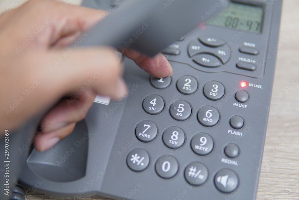 Male hand holding telephone and dailing a phone number. Male hand holding telephone and dailing a phone number.