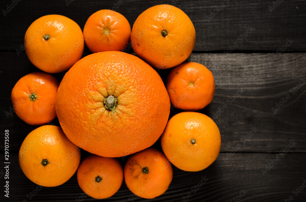 Raw several mandarins and orange isolated on black wooden table
