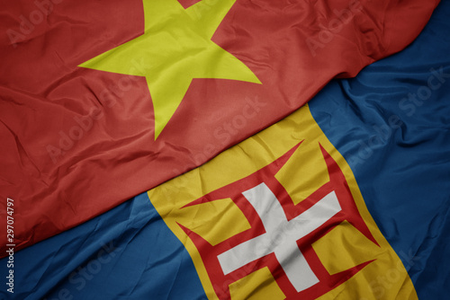 waving colorful flag of madeira and national flag of vietnam.