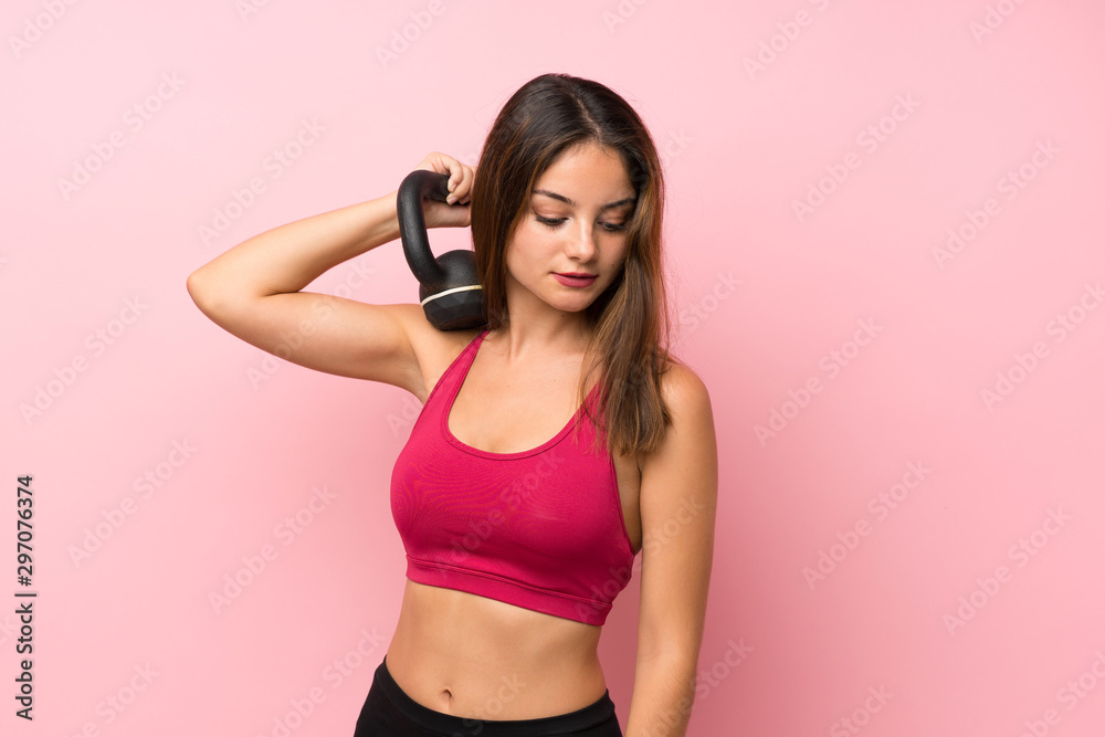 Young sport girl over isolated pink background making weightlifting with kettlebell Young sport girl over isolated pink background making weightlifting with kettlebell