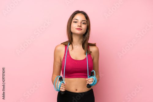 Young sport girl over isolated pink background with jumping rope © luismolinero