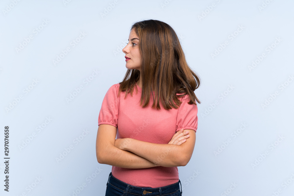 Young brunette girl over isolated blue background looking side Young brunette girl over isolated blue background looking side