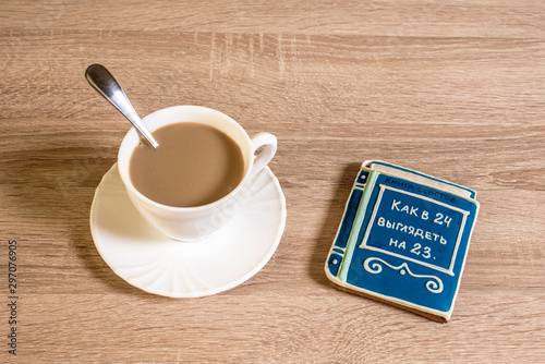 cup of morning coffee latte on a table with cookies in the form of a small book