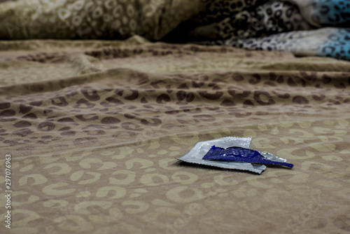 open condom packaging lies on the bed