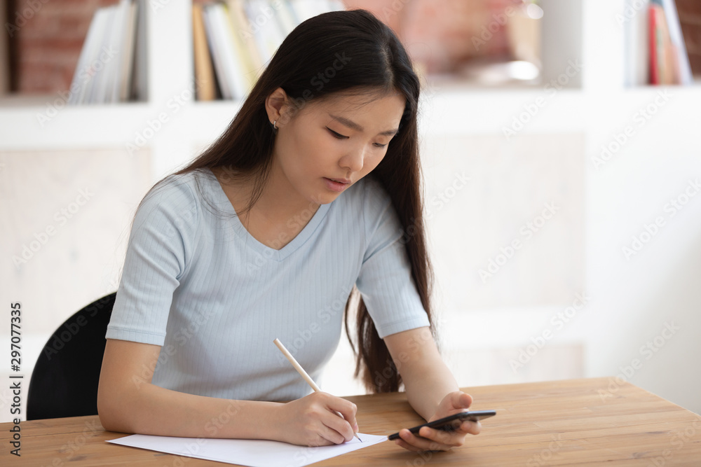 Vietnamese student using app downloaded on phone studying seated indoors Vietnamese student using app downloaded on phone studying seated indoors