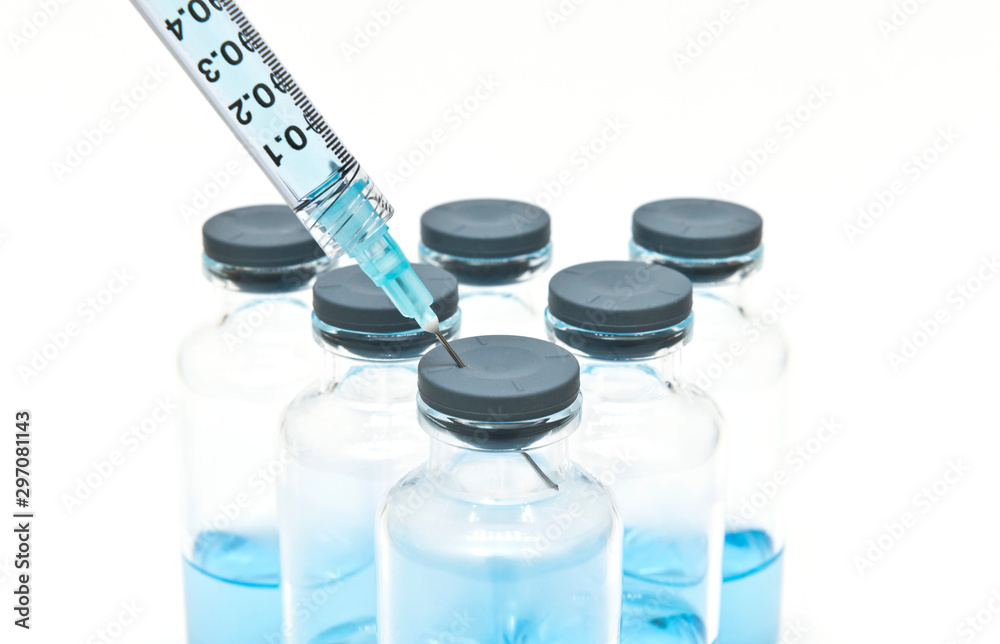 Close up of syringe and medical vials containing blue liquid medicine on the white background Close up of syringe and medical vials containing blue liquid medicine on the white background