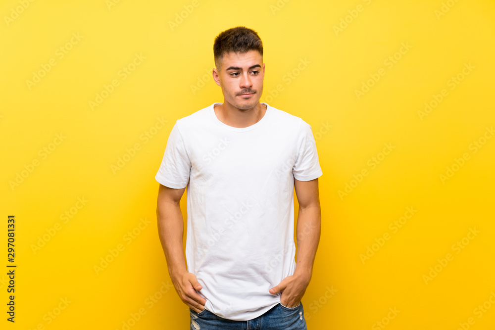 Young handsome man over isolated yellow background making doubts gesture looking side Young handsome man over isolated yellow background making doubts gesture looking side