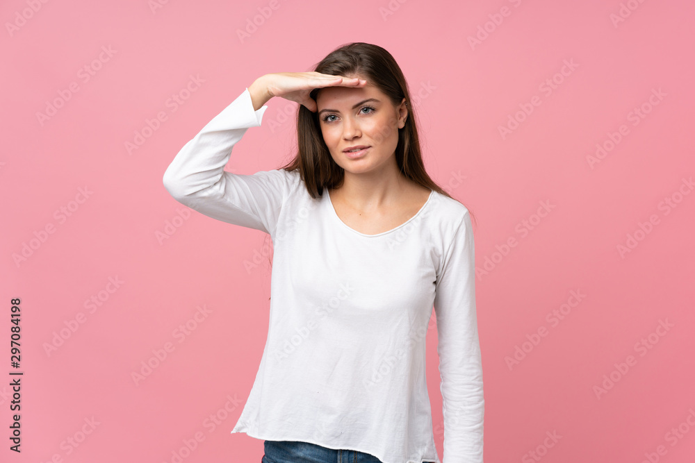 Young woman over isolated pink background looking far away with hand to look something Young woman over isolated pink background looking far away with hand to look something