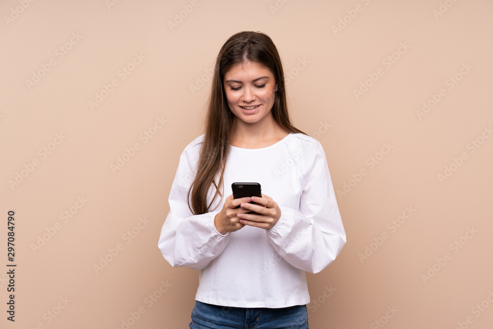 Young girl over isolated background sending a message with the mobile Young girl over isolated background sending a message with the mobile
