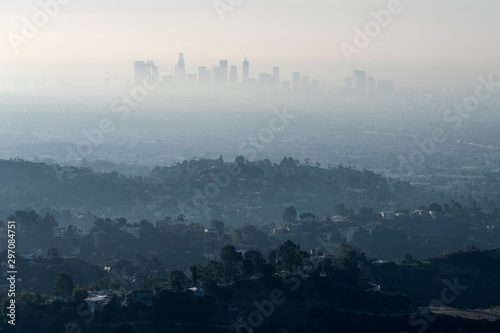 Thick hazy layer of smog and smoke from nearby brush fire clouding the view of downtown Los Angeles buildings in Southern California. Shot from hilltop in popular Griffith Park.