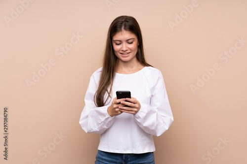 Young girl over isolated background sending a message with the mobile
