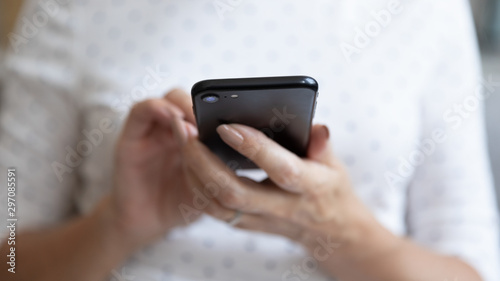 Senior woman holding smartphone using mobile app, close up view