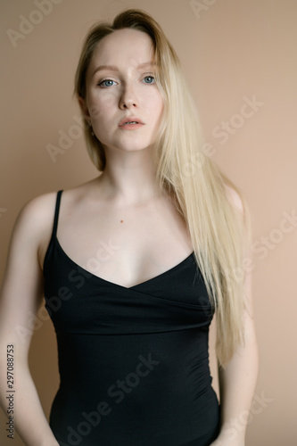Graceful young woman in a black top posing against beige wall. © Vladimir Arndt