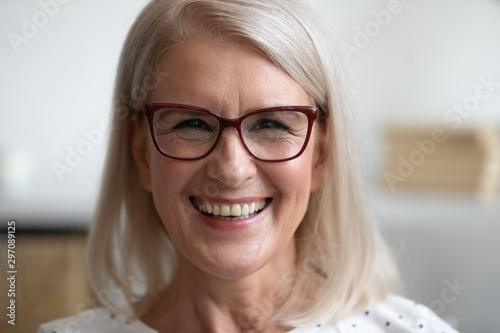 Happy older woman looking at camera at home, closeup portrait