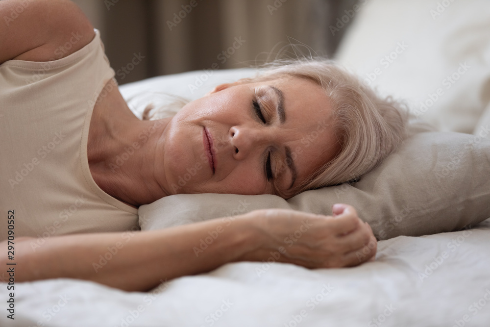 Calm serene older woman sleeping alone in bed, closeup view Calm serene older woman sleeping alone in bed, closeup view