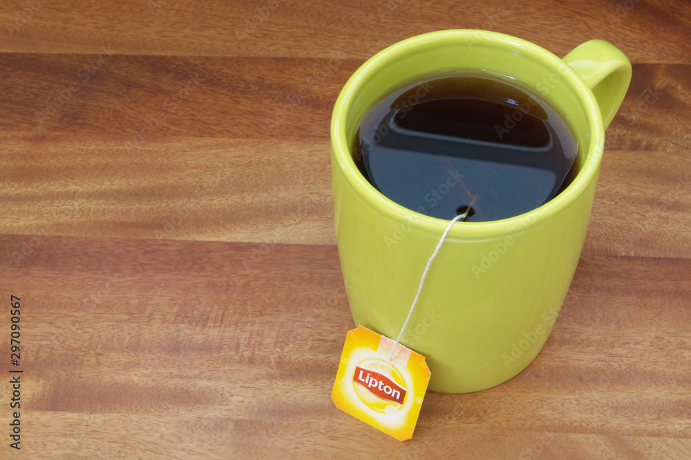 Fotka „ Lipton tea in cup with tea bag on wooden table. Lipton is one of  the famous brands in tea industry. “ ze služby Stock | Adobe Stock