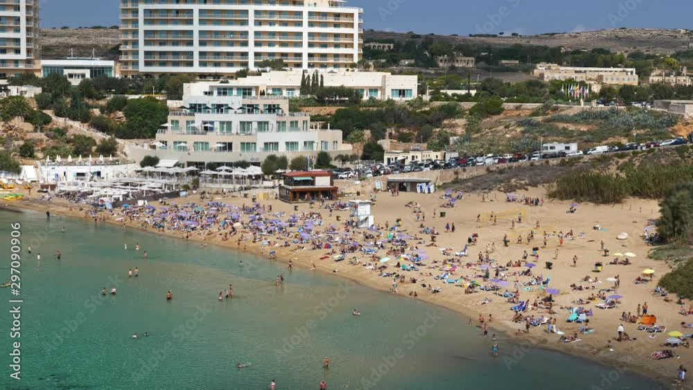 Golden Bay sandy beach in Malta, people relaxing and sunbathing, elevated view from distance Golden Bay sandy beach in Malta, people relaxing and sunbathing, elevated view from distance