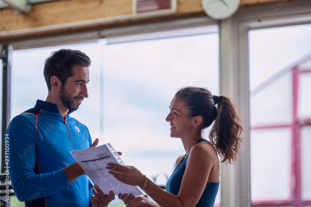 Obraz premium Fit woman talking to her trainer at the gym