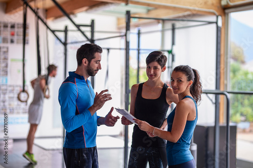 Gym instructor assisting two sporty women  in fitness center.Concept of exercises photo