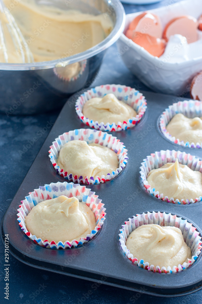 Raw muffins in a metal mold before baking, selective focus Raw muffins in a metal mold before baking, selective focus